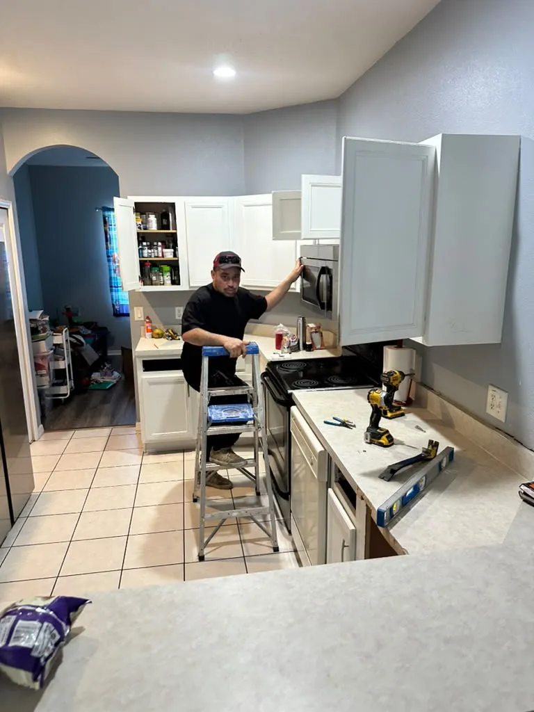 Yoll Remodeling installer mounting a wall cabinet during a kitchen remodel in Orlando