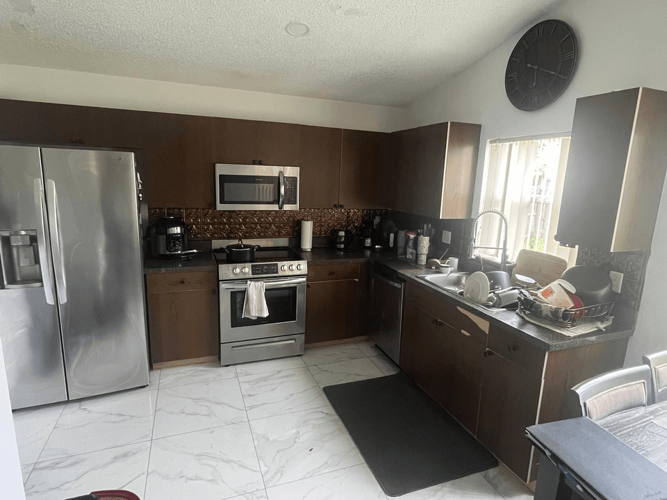 The same Orlando kitchen before and after a Yoll Remodeling Smart Refresh: dark brown cabinets and laminate countertop, then sage green shaker cabinets, brass pulls and white quartz countertops